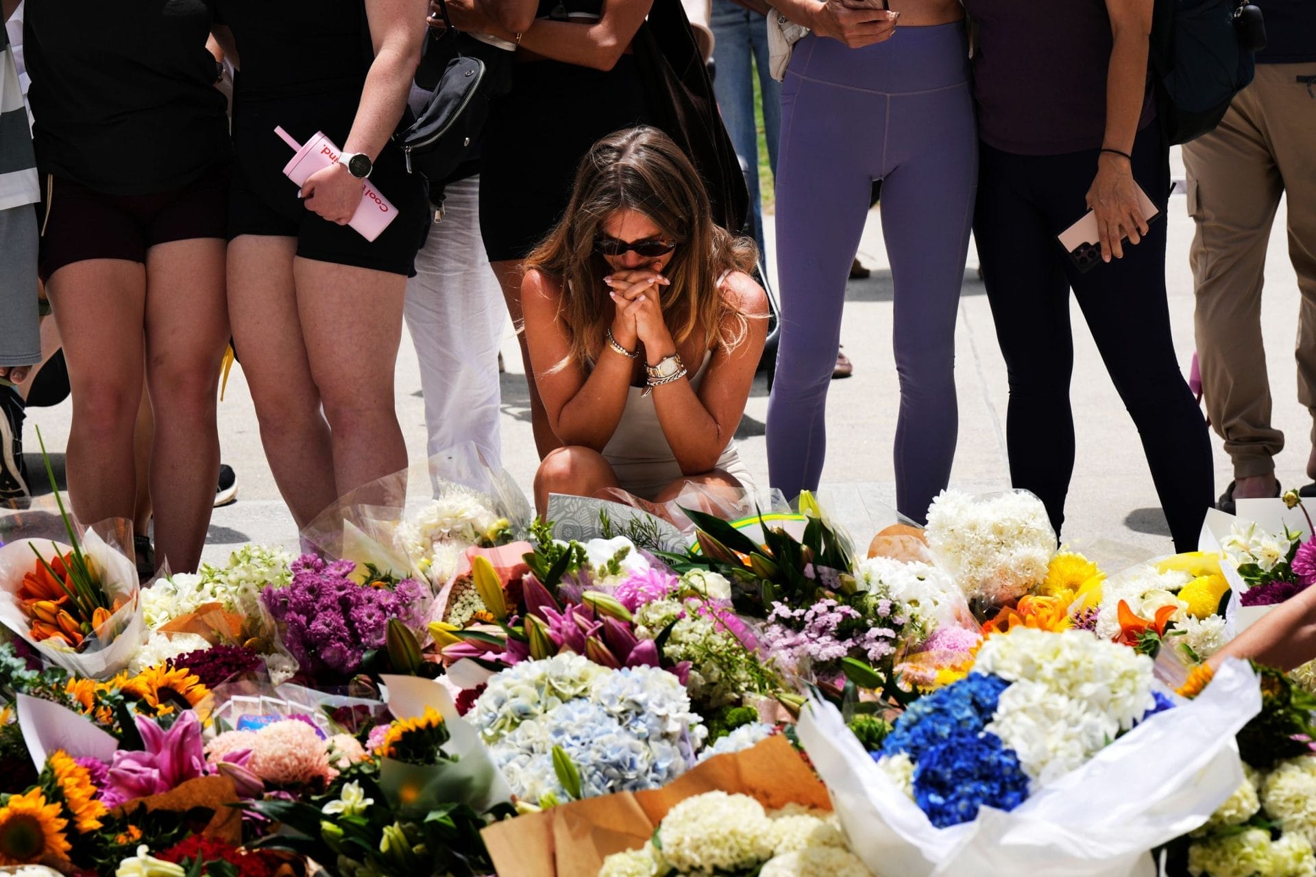 Bondi Beach Tragedy 2025 | Woman praying at flower memorial Bondi Beach Sydney December 2025 - Photo by Mark Baker Associated Press